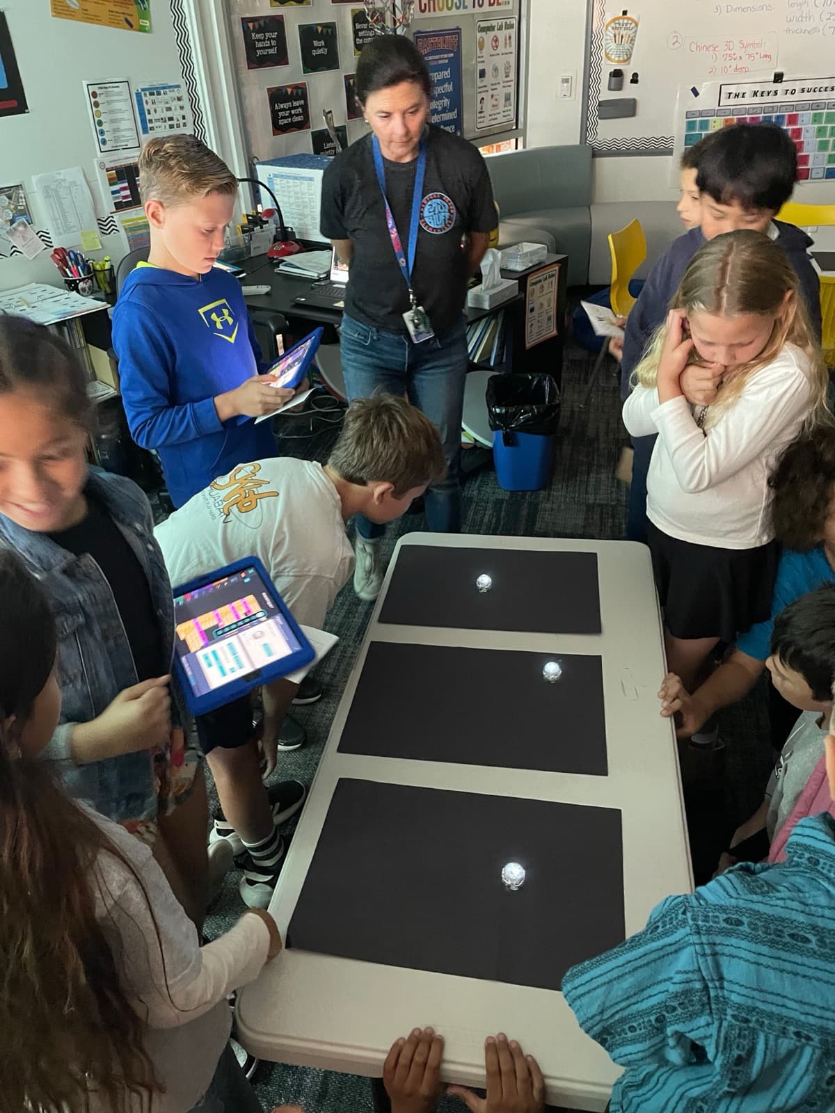Eastbluff students gathered around glowing programmable robots in the Otter Lab